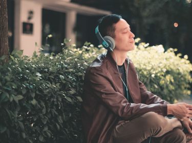 Junger Mann hört sich Apple-Music-Inhalte mit dem Smartphone an.