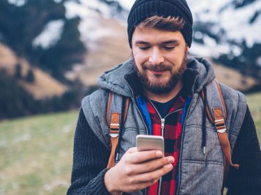 Junger Mann nutzt den Facebook Messenger am Smartphone.