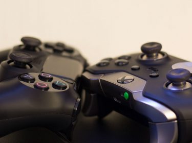 Ein PS4- und Xbox-One-Controller liegen auf dem Tisch.