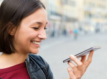 Junge Frau nutzt Bixby am Smartphone auf Deutsch.