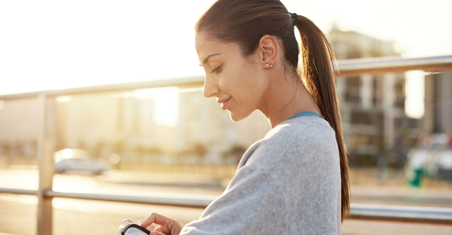 Junge Frau tippt auf das Display ihres Fitbit-Trackers.