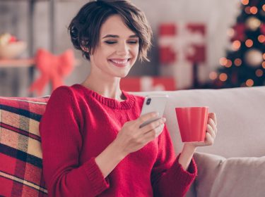 Frau schaut lächelnd auf ihr Handy.