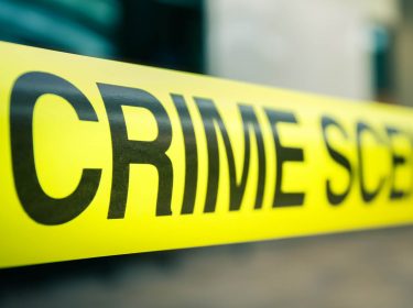 Gelbes Absperrband mit der Aufschrift „Crime Scene Do Not Cross”.