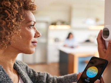 Eine Frau stellt einen smarten Thermostat ein.