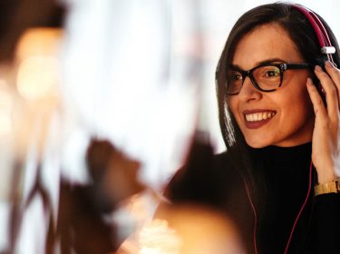 Junge Frau hört am Mac via iTunes Musik.