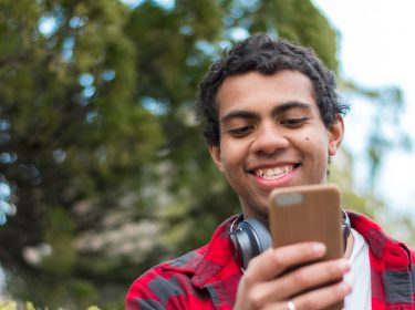 Junger Mann löst am Smartphone sein Twitter-Problem.