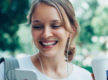 Junge Frau spielt via Smartphone Podcast ab.