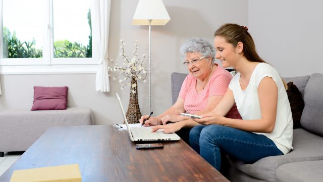 Frau zeigt Mutter Online-Funktionen am Laptop