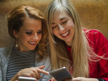 Freundinnen vergleichen ihre Smartphones miteinander.