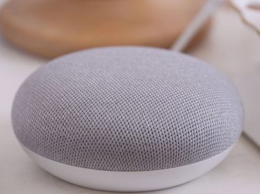 Der Musik abspielende Google-Home-Lautsprecher steht auf einem Tisch.