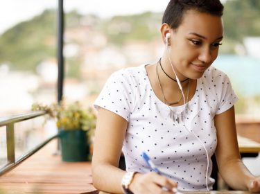 Junge Frau hört am MacBook via iTunes Musik.