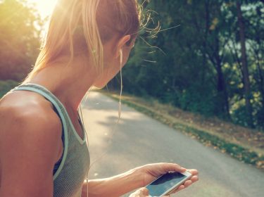 Junge Frau hört über ihre Kopfhörer Musik von Deezer.