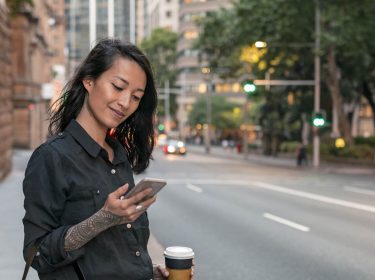 Junge Frau sieht sich auf dem Smartphone ein WhatsApp-Profilbild an.