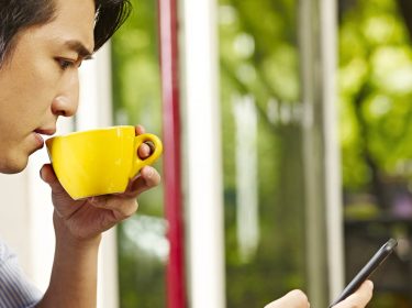 Junger Mann testet am Smartphone Android 10.