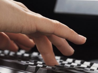 Menschliche Hand drückt Tasten auf der Tastatur.