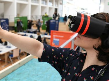 Eine Frau trägt eine VR-Brille und erlebt Inhalte in der virtuellen Realität.