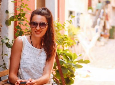 Junge Frau hält ihr Smartphone in der Hand, das einen Passwort-Manager installiert hat.