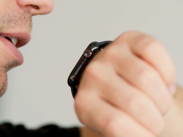 Mann hält seinen Mund nahe der Apple Watch, um Siri aufzurufen.