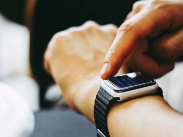 Hand tippt auf das Apple-Watch-Display, um ein Update anzustoßen.