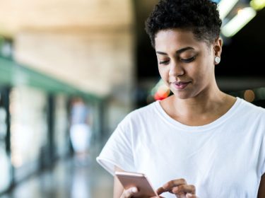 Junge Frau lädt die iOS-13-Beta auf ihr iPhone herunter.