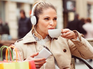 Junge Frau hört mit dem Smartphone Musik aus ihrer Deezer-Playlist.
