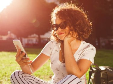 Junge Frau ändert die Deezer-Sprache am Smartphone.