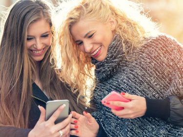 Freundinnen informieren sich am Smartphone über die Übertragung von Threema-IDs.