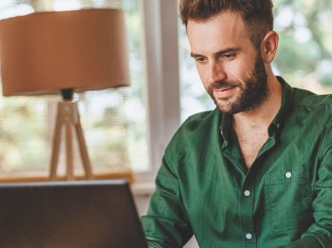 Mann tippt in Microsoft Word am Laptop.