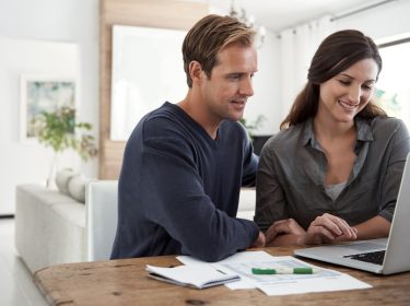 Eine Frau erklärt ihrem Mann, wie er Dateien mit Dropbox Transfer versendet.