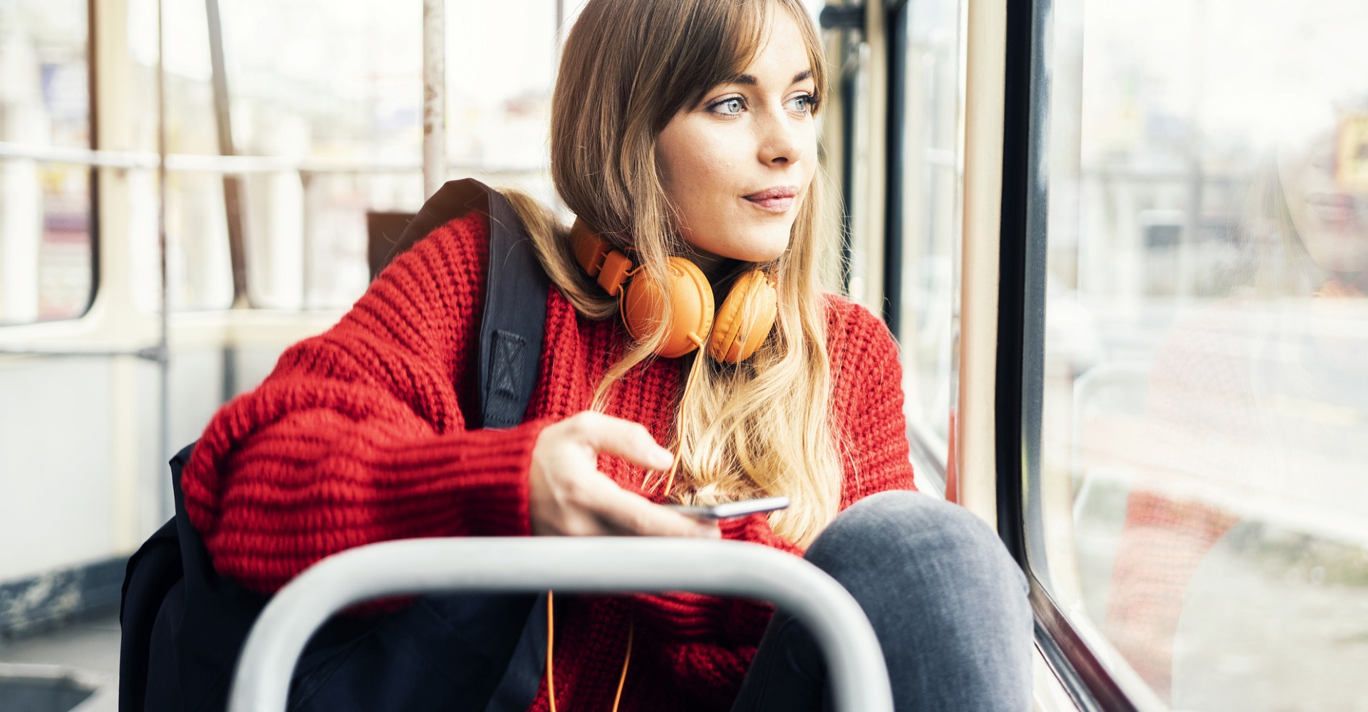 Junge Frau sitzt im Bus und hört ihre Lieblingsmusik.