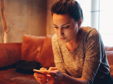 Junge Frau auf Sofa teilt eine Instagram-Story