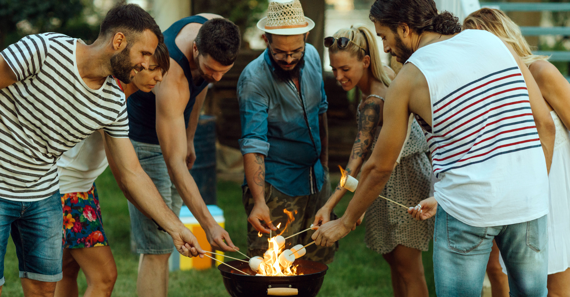 Junge Leute stehen mit Marshmallows am Grill