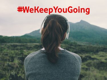 Frau mit Köpfhörern hört Reise-Poscasts und blick dabei in die Landschaft