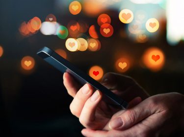 Handy in Händen und Herz-Icons