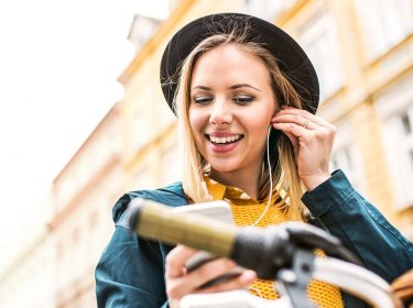 Junge Frau hört via iPhone wieder Musik mit Apple Music.