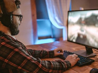 Junger Mann sitzt an PC und testet Gaming-Tipps