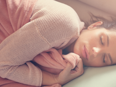 Frau schläft im Bett ein.