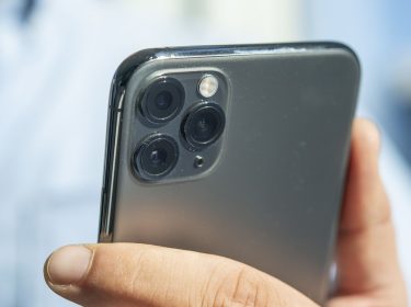 Mann drückt eine Taste am iPhone 11, um das Gerät auszuschalten.