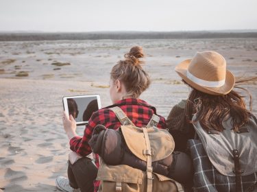 Zwei Mädchen mit Tablet am Strand