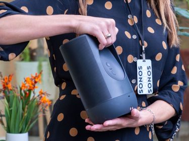 Frau hält den mit Spotify verknüpften Sonos-Lautsprecher in der Hand.