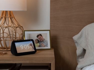 Der Amazon Echo Show 5 steht auf einem Nachttisch neben dem Bett.
