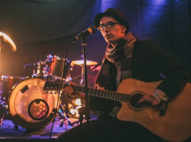 Mann mit fehlenden Finger kann durch Instrumente für Menschen mit Behinderung Gitarre spielen.