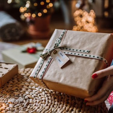 frau-verschenkt-geschenk-in-dem-smarter-schmuck-eingepackt-ist Frau verschenkt Päckchen, in dem smarter Schmuck eingepackt ist.
