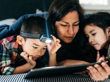 Eine Mutter surft mit ihren Kindern zuhause auf einem Tablet