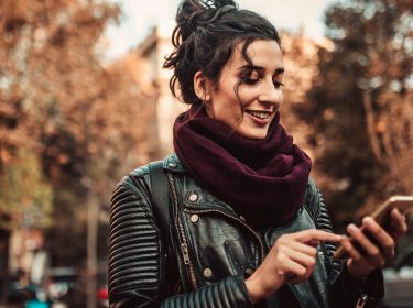 Frau schaltet den Dark Mode von WhatsApp am Smartphone ein.