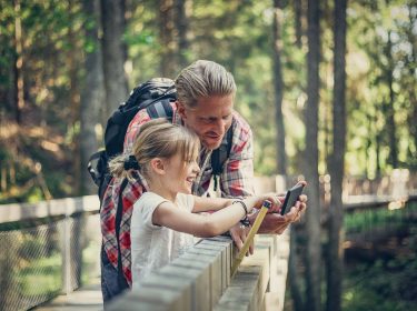 vater und kind nutzen smartphone im wald
