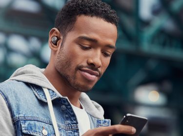 Junger Mann mit Jabra Elite 75t und Smartphone