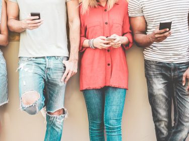 Smartphone Trends 2020: Junge Leute stehen mit Smartphone nebeneinander