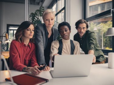 Eine Gruppe Personen arbeitet gemeinsam an einem Laptop