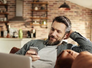 Mann mit Smartphone im Wohnzimmer